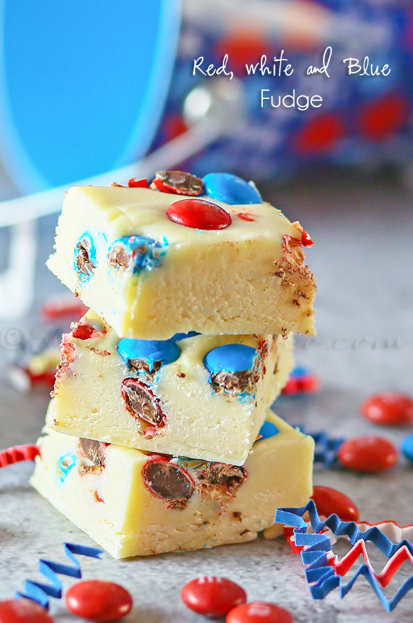Red, White & Blue Fudge stacked up on a cutting board with M&M's lying around.