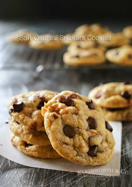 These Soft Oatmeal Snickers Cookies are a thick & chewy oatmeal cookie stuffed full of Snickers candy bars & chocolate chips. So easy & so yummy too! Definitely the best oatmeal cookie recipe around! Don't miss the tip on how to make those chocolate chips look so perfect too!