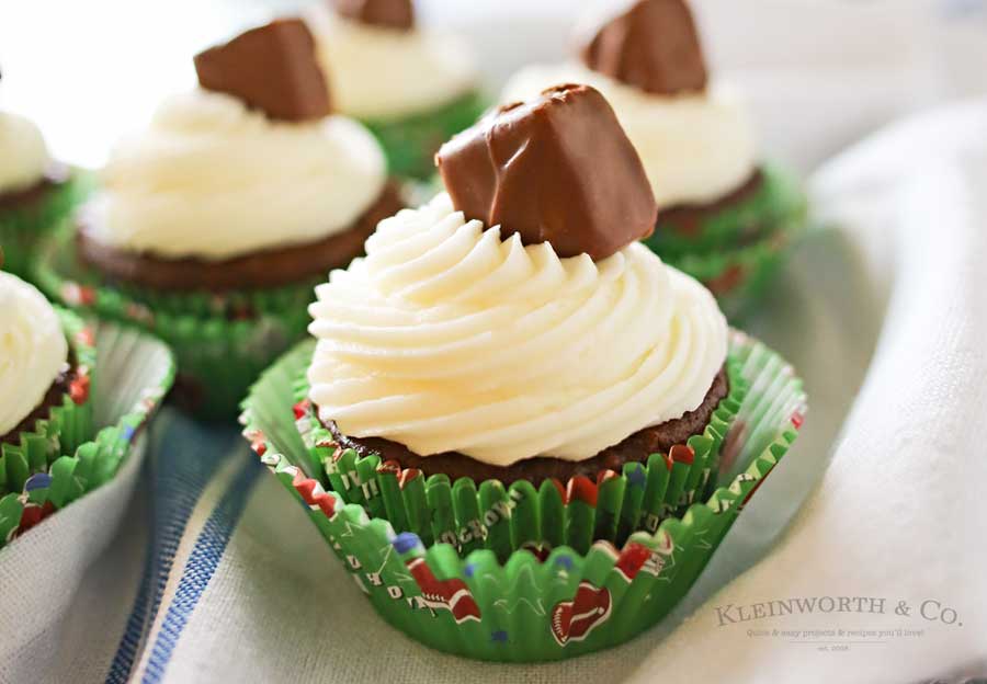 Looking for some game day food ideas? Game Day Snickers Cupcakes are an easy 3 - ingredient cupcake recipe loaded with Snickers candy bars, topped with a delicious & easy buttercream frosting & more Snickers minis. on kleinworthco.com