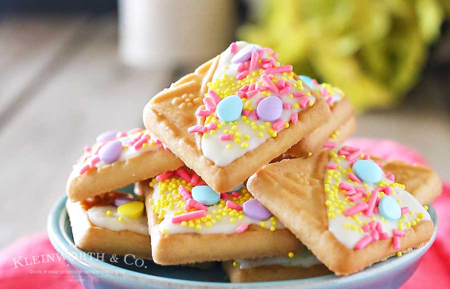 Looking for a quick little treat to serve at all your Easter gatherings? Creating cute treats like these White Chocolate Spring Cookies for Easter is easy. Simple shortbread cookies, white chocolate & Easter sprinkles is so much fun! These literally take about 15 minutes to make & everyone just loves them. People will think you slaved away in the kitchen for hours. They are an adorable Easter dessert that bring BIG smiles! 