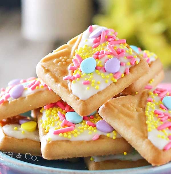 Looking for a quick little treat to serve at all your Easter gatherings? Creating cute treats like these White Chocolate Spring Cookies for Easter is easy. Simple shortbread cookies, white chocolate & Easter sprinkles is so much fun! These literally take about 15 minutes to make & everyone just loves them. People will think you slaved away in the kitchen for hours. They are an adorable Easter dessert that bring BIG smiles!