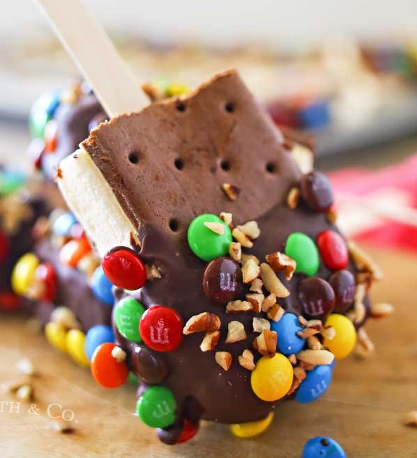 Ice Cream Sandwich Pops are an easy summer treat to make. Made with a simple ice cream sandwich, chocolate & decorations they are a perfect frozen treat. Make some for all of your celebrations, holidays & backyard BBQ's this summer.