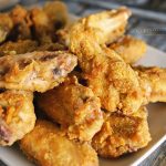 Close-up of crispy seasoned chicken wings, perfectly golden-brown, piled on a plate, highlighting their crunchy exterior and flavorful seasoning.