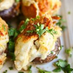 Garlic Parmesan clam-stuffed mushrooms arranged on a plate, topped with fresh herbs, showcasing a golden-brown crust and savory filling."